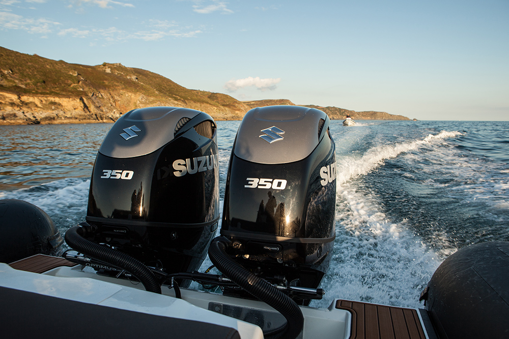 Twin Suzuki 350 outboards powering a RIB along a rocky coastline at speed