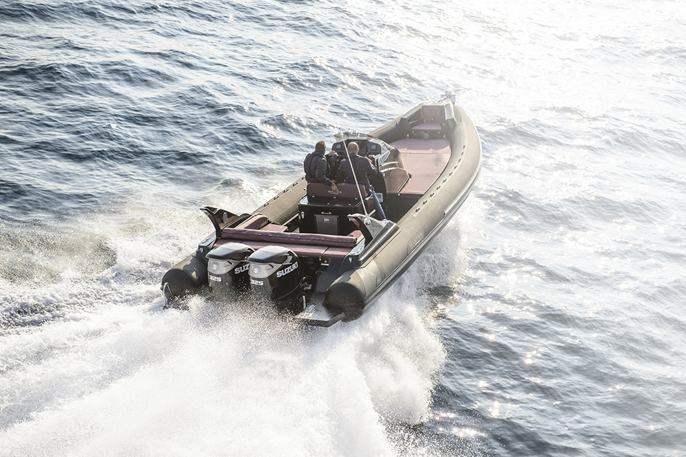Twin Suzuki DF325 outboards powering a RIB at speed through choppy water with two people at the helm.