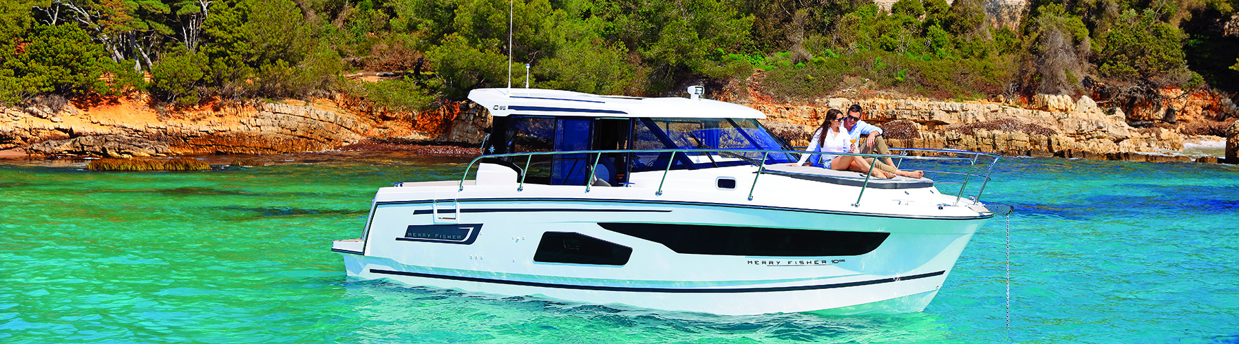 Merry Fisher 1095 with couple relaxing on the bow sun bed on a turquoise sea at anchor