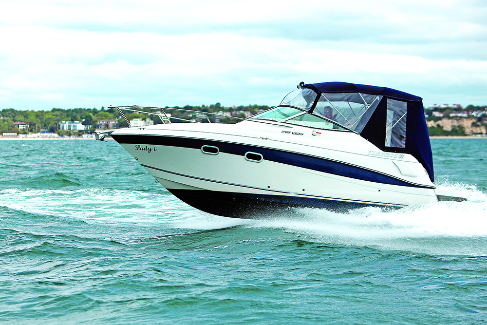 Four Winns motor cruiser running at speed offshore with spray, showing planing hull performance in choppy water.