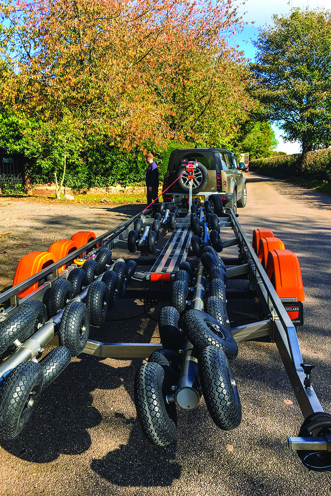 Vanclaes boat trailer with gyro roller system hitched to Land Rover Defender on country lane, ready for boat loading.