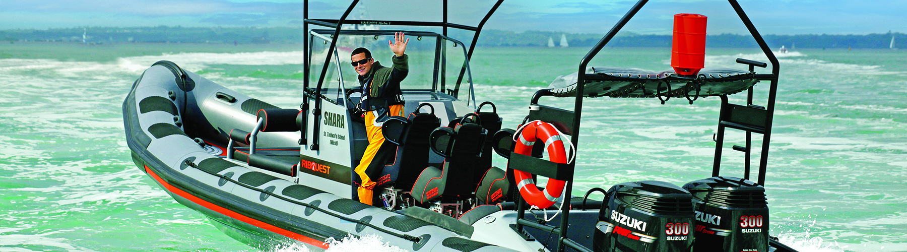 Bear Grylls on board his Ribcraft RIB at sea waving back at the camera