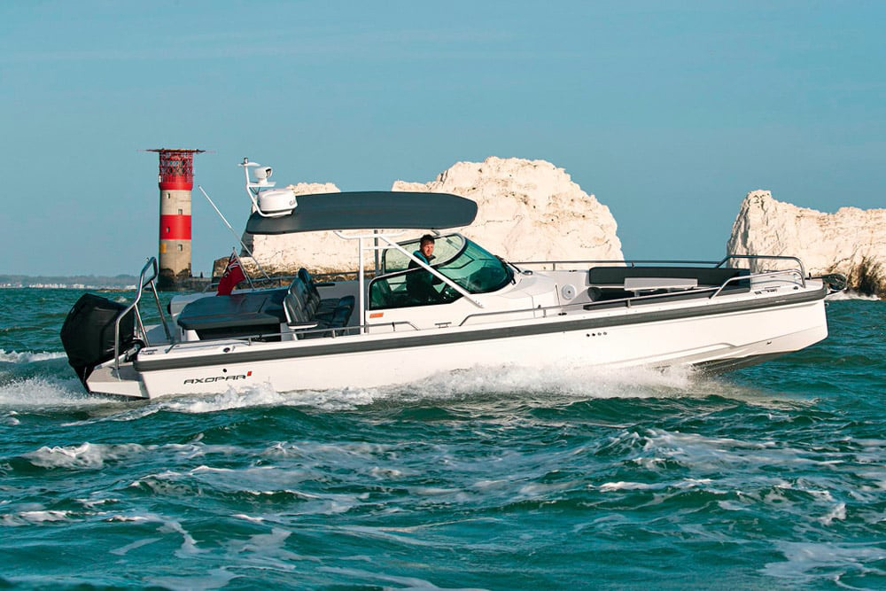 Axopar adventure boat running close to the Needles lighthouse, Isle of Wight, with visible tidal flow and standing waves around the headland