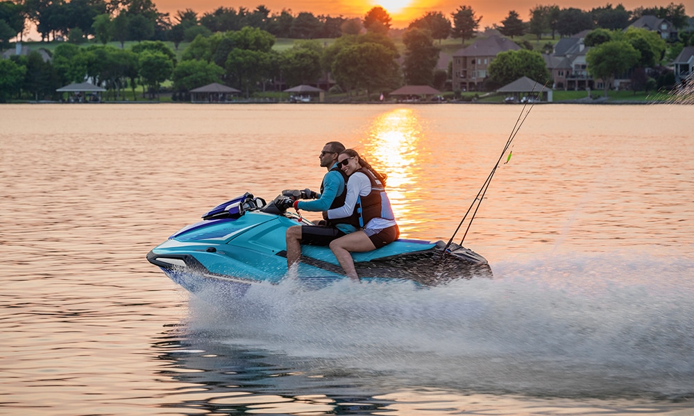 VXDELUXE_web Couple on a PWC in the evening with sunset behind, woman is resting her head on shoulders of the male driver, romantic scene