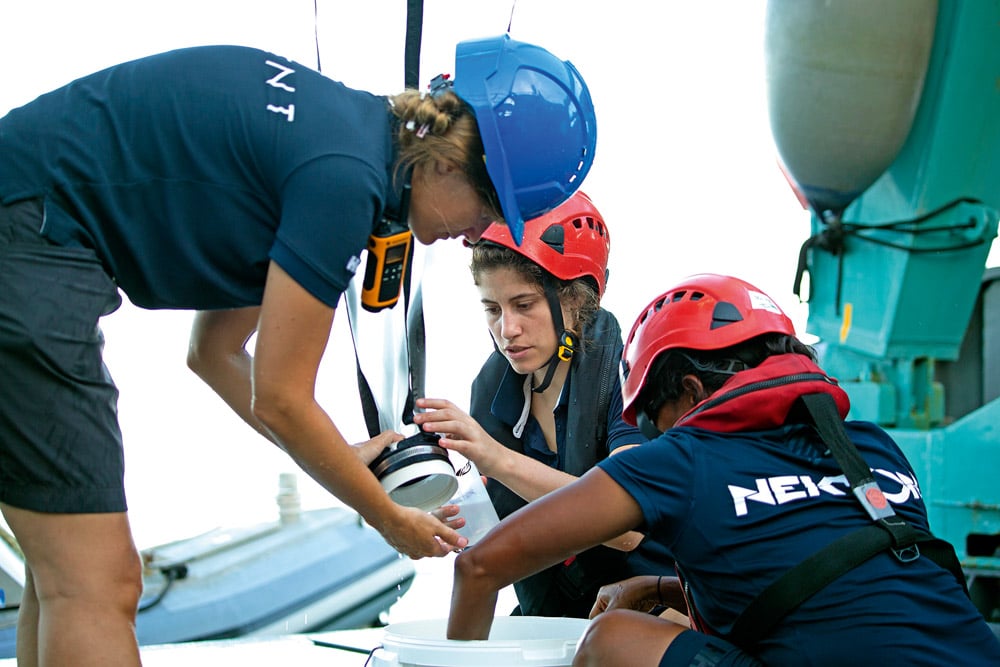 Scientists aboard a research vessel cleaning a net used to collect zooplankton.