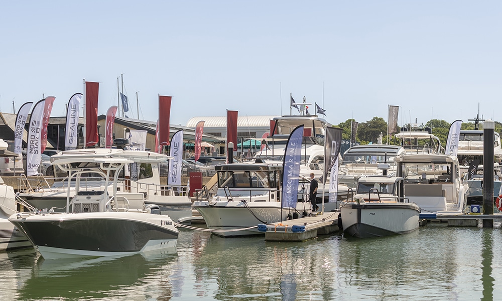 Motor yachts and powerboats docked at Swanwick Marina during the 2025 British Motor Yacht Show, with branded flags and clear skies.
