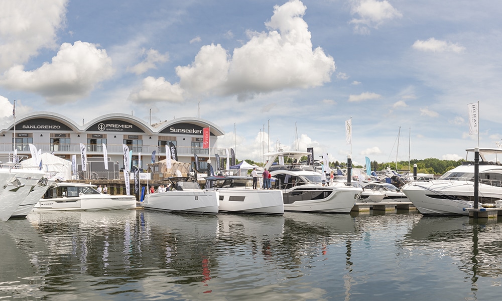 View of boats moored up at marina with boathouse in background.