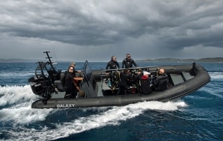 Galaxy RIB with dive crew and equipment underway at speed in open water.