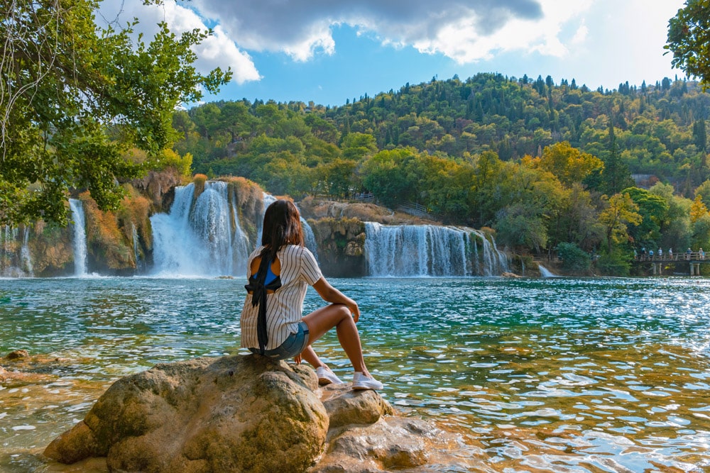 KRKA waterfalls Croatia during summer, young women watch the waterfalls of krka national park Croatia on a bright summer evening in the park.
