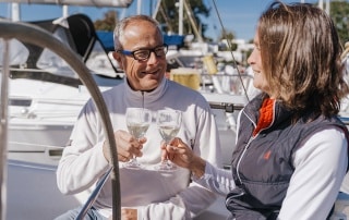Couple enjoying wine aboard a docked yacht at a marina.