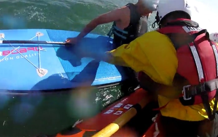 RNLI lifeboat crew assist Mark Parker, a paddleboarder in distress, during a sea rescue.