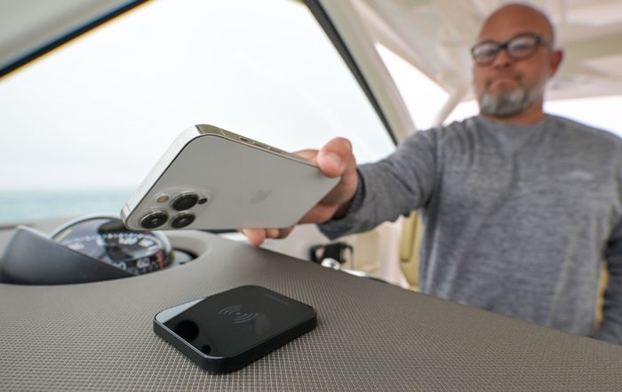 Man places phone onto Scanstrut Ultra MagSafe wireless charger on a boat console.