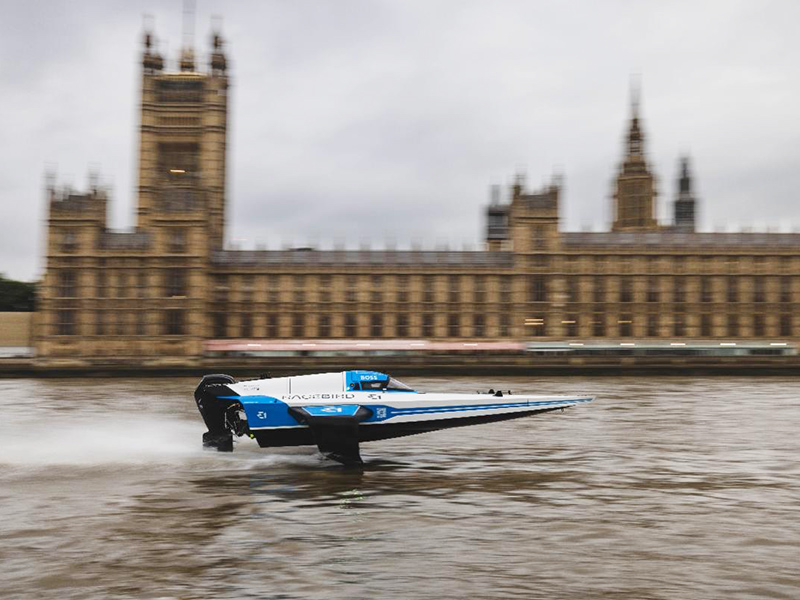 E1 electric RaceBird hydrofoil speeding along the River Thames with the Houses of Parliament in the background.