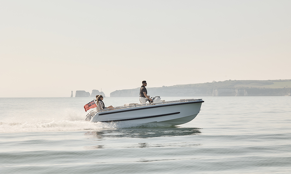 Couple cruising on an Evene Tender's Origin Series in calm coastal waters, with iconic cliffs in the background.
