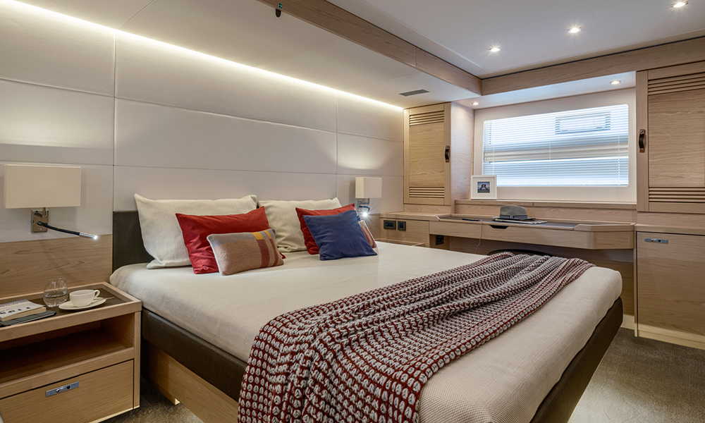 Luxurious master cabin aboard the BENETEAU Grand Trawler 63 featuring modern wood finishes, ambient lighting and a double bed.