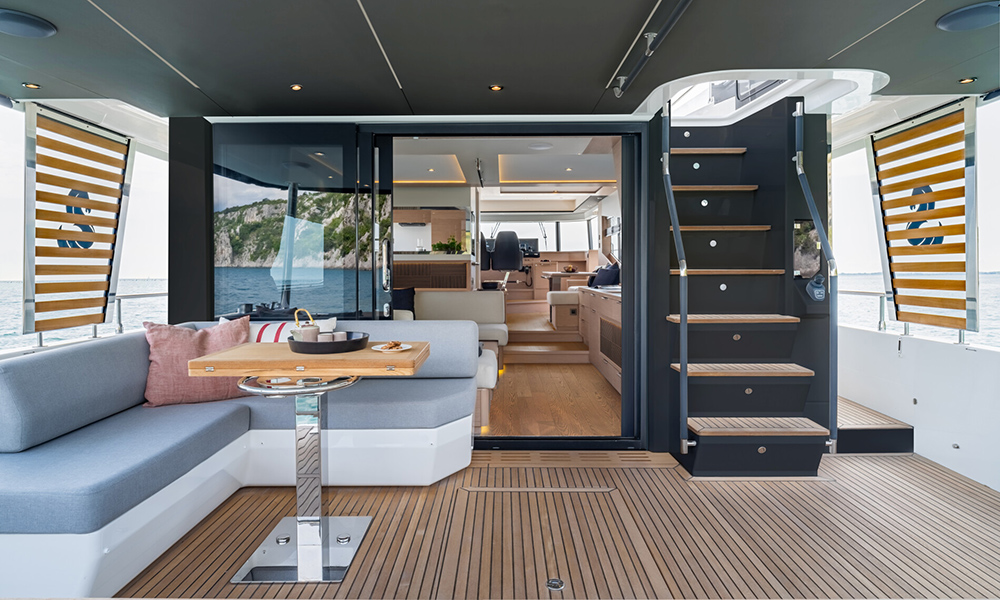 Aft cockpit of the BENETEAU Grand Trawler 63 with teak decking, shaded seating area, dining table.