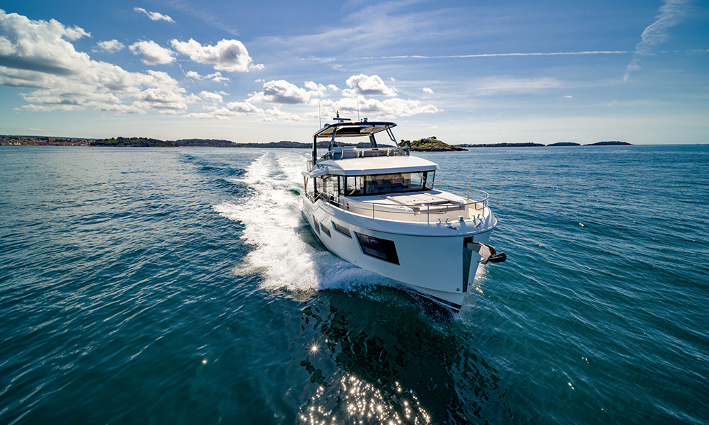 BENETEAU Grand Trawler 63 cruising at speed in open water, under clear skies.