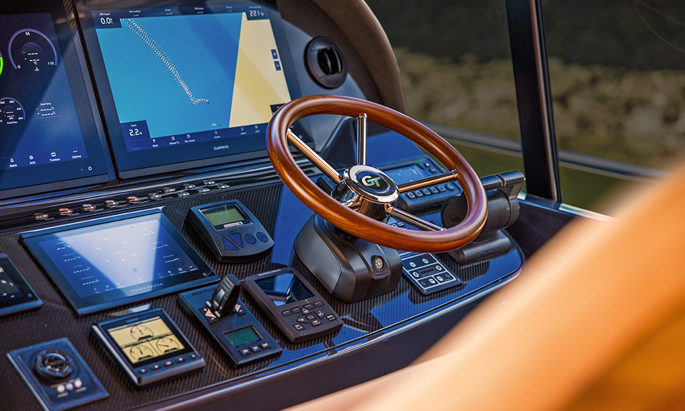 Polished teak helm with integrated Garmin navigation screens and precision jet controls aboard the custom Palm Beach GT60 Jet Drive.