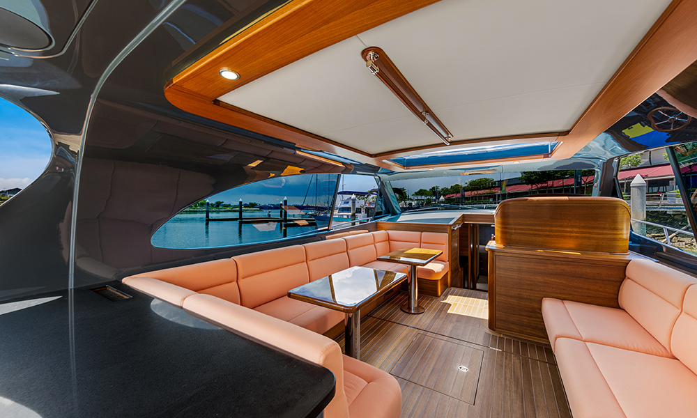 Spacious salon aboard the Palm Beach GT60 Jet Drive featuring wraparound blush seating and teak finishes