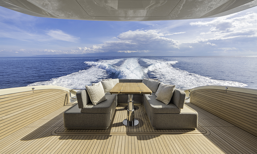 Aft deck of Invictus ST550 featuring teak flooring, cushioned lounge seating and table.