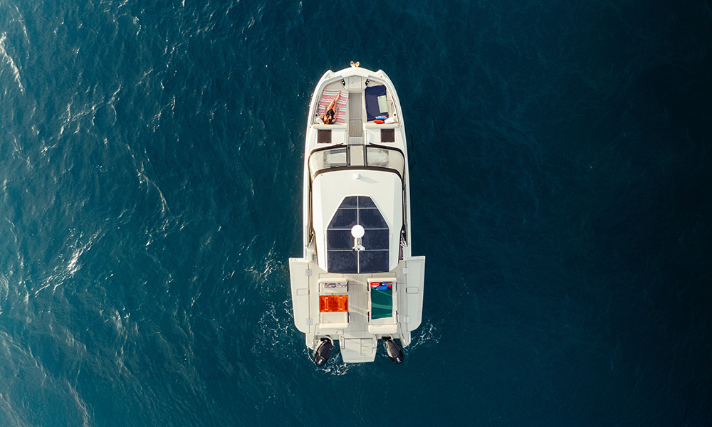 Top-down view of YOT41 catamaran anchored at sea, showing spacious deck, solar panel roof, and sunbather relaxing at the bow.
