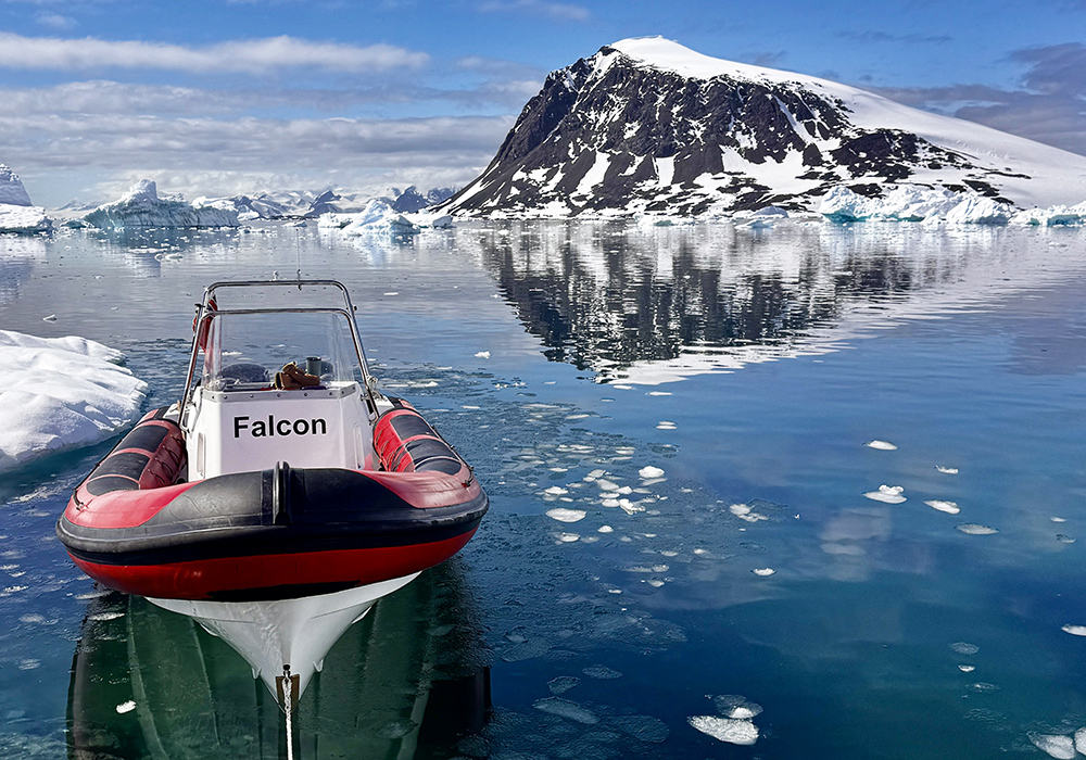Red Island RIB moored in beauitful blue water with icebergs and snowy mountains behind