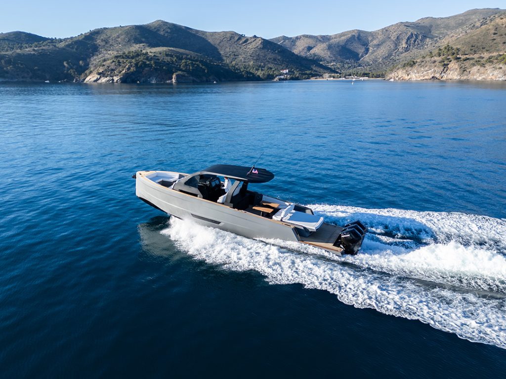 Maxim Yachts' Max 43 Comfort cruising at speed on calm blue water with mountainous coastline in the background.