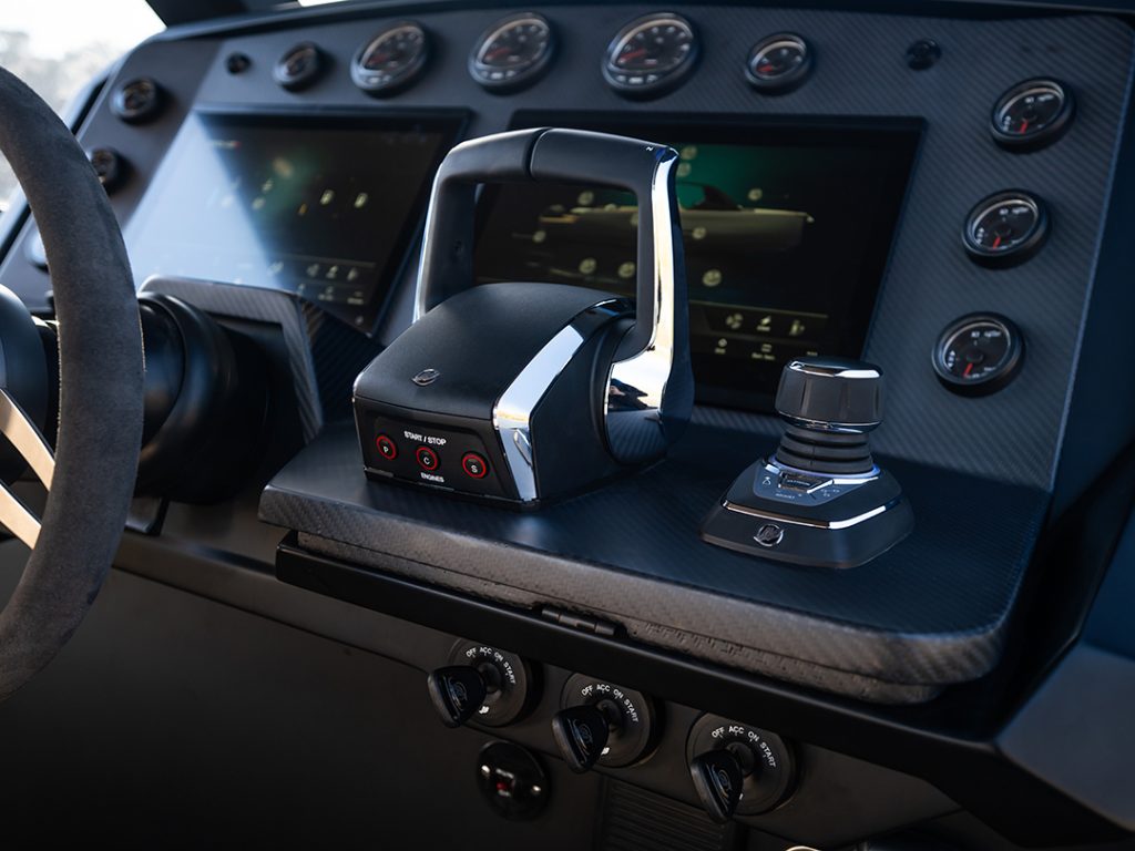 Close-up of Maxim Yachts' Max 43 Comfort’s carbon fibre helm with dual throttle controls, joystick, analogue gauges, and touchscreen displays.