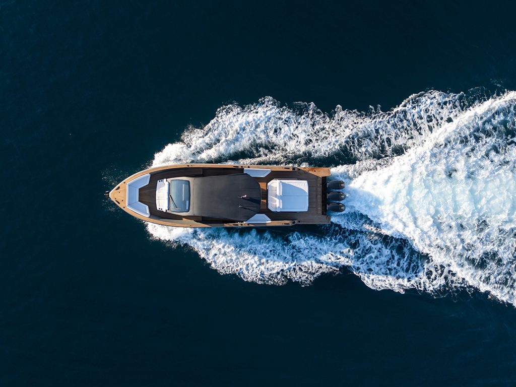 Aerial view of Maxim Yachts' Max 43 Comfort daycruiser powering through deep blue water, leaving a white wake behind.