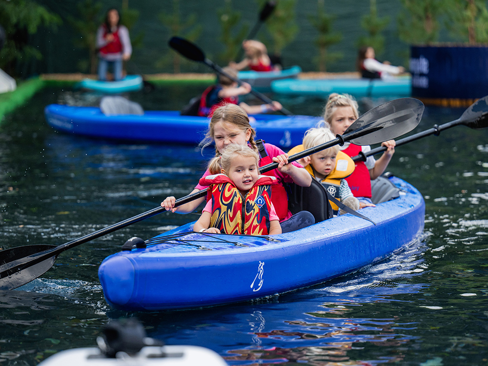 Children paddling blue kayaks in a supervised pool activity at Southampton International Boat Show.