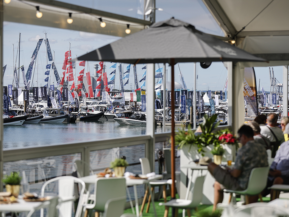 Visitors relax in a waterfront dining area overlooking Southampton International Boat Show marina.