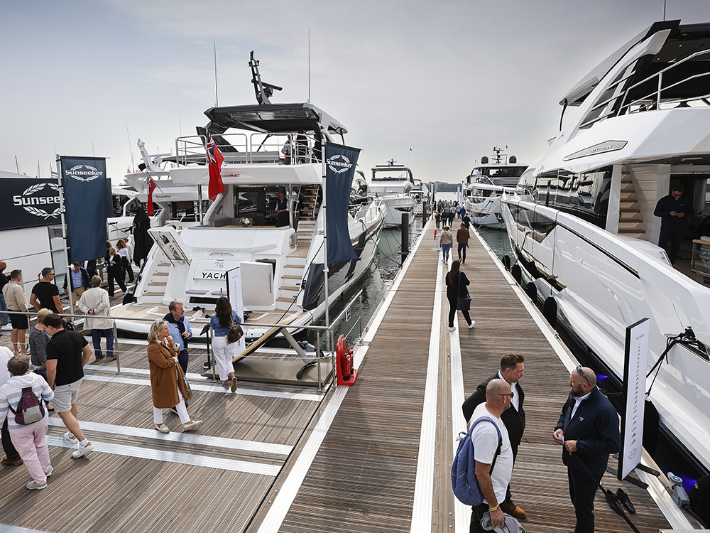 Visitors walking along pontoons at Southampton Boat Show, viewing luxury yachts.