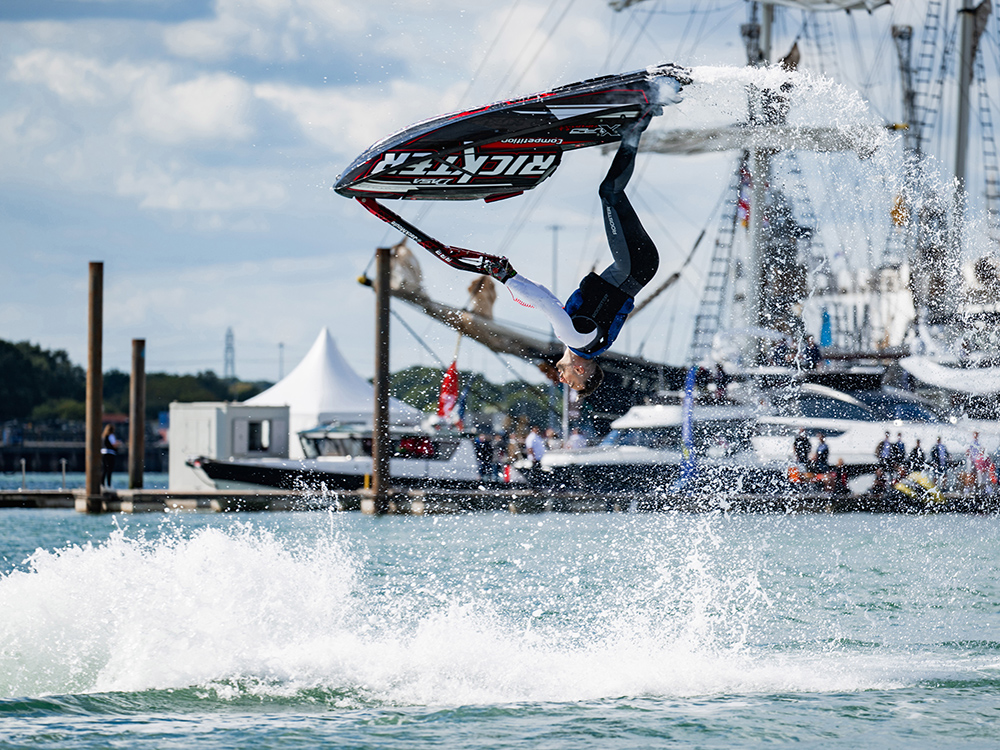 Freestyle jet ski rider performs a backflip over the water during a high-energy stunt show at Southampton International Boat Show.