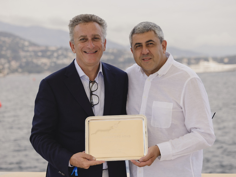 Alejandro Agag and General Zurab Pololikashvili stand smiling by the waterfront in Monaco, holding a commemorative plaque