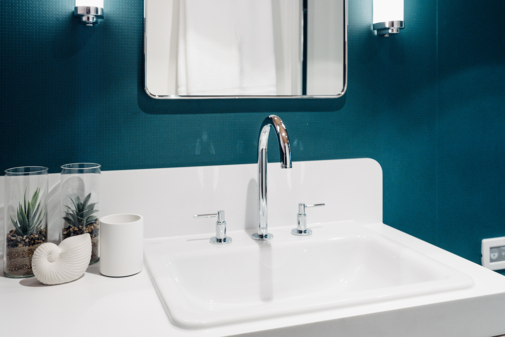 Image of white basin with mirror on the wall behind and sea green painted walls