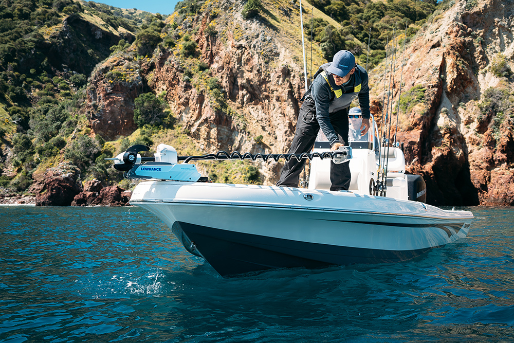 Image of boat on turquoise sea with man lifting up Lowrance Recon