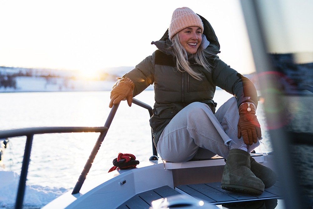 Helene Olafsen - former Snowboardcross world champion - sitting on the bow of a boat smiling