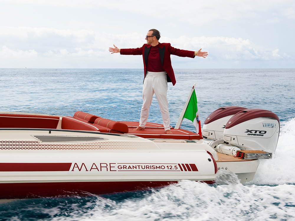 Alessandro Martorana stands on the GranTurismo 12.5 AMare stern with arms wide.