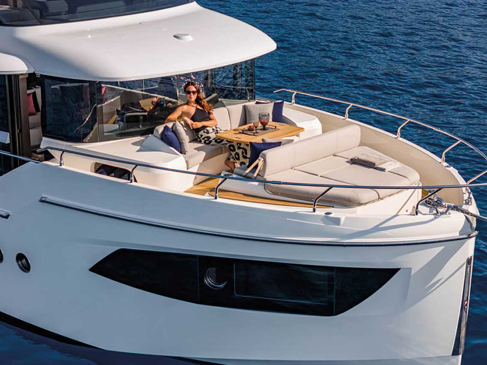 Woman relaxing on the bow lounge of the Absolute Navetta 53, with sunpads, table, and sea views.