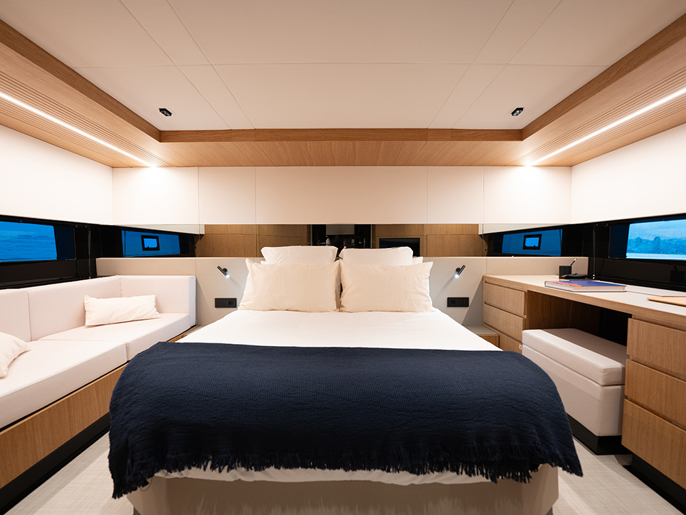 Luxury De Antonio D60 master cabin with central bed, sofa seating, desk area and modern wood finishes illuminated by soft lighting.