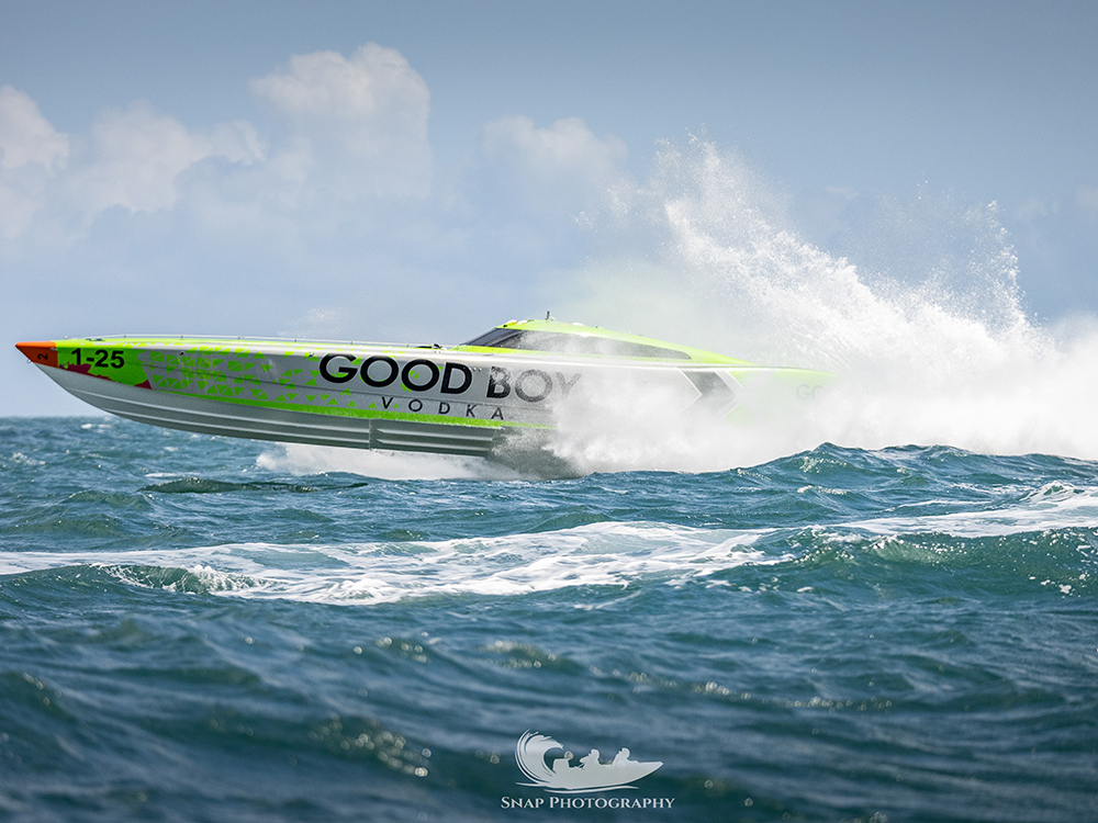 Good Boy race boat races across choppy seas at speed, spraying water.