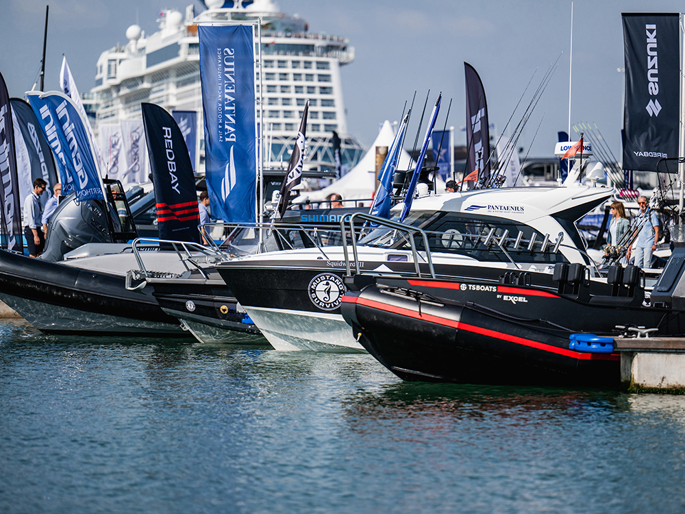 Powerboats and RIBs lined up with branded flags at Southampton International Boat Show marina.