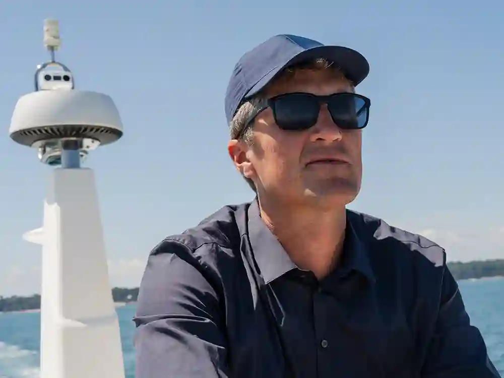 Man at sea with SEA.AI Watchkeeper mast system in background.