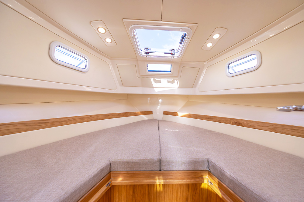 Double berth with grey upholstery and light wood finishings.