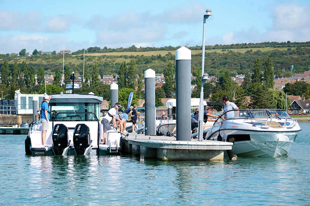 Boats mooring alongside dry stack pontoon on a sunny day.