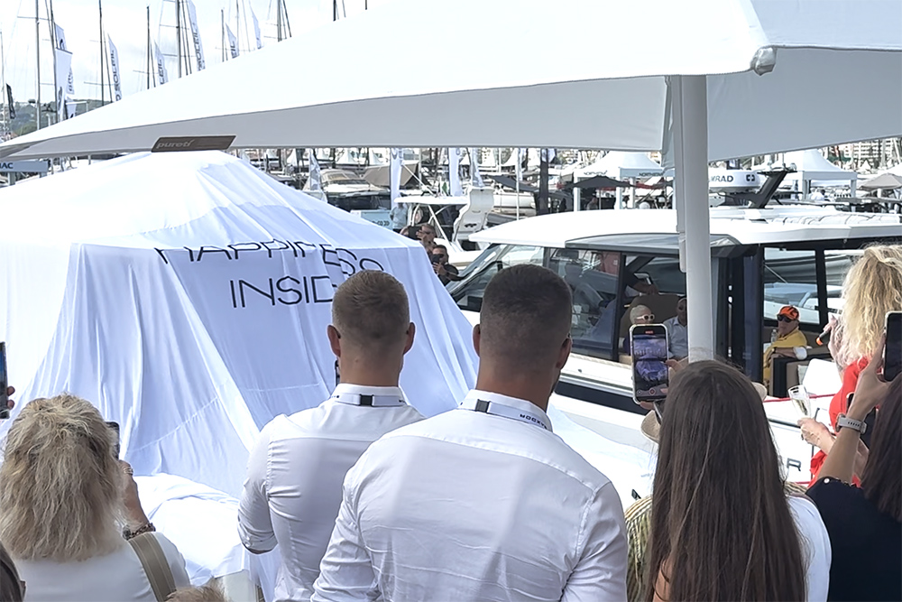 People stood around with phones and cameras looking at the Saxdor 400GTS covered with a sheet