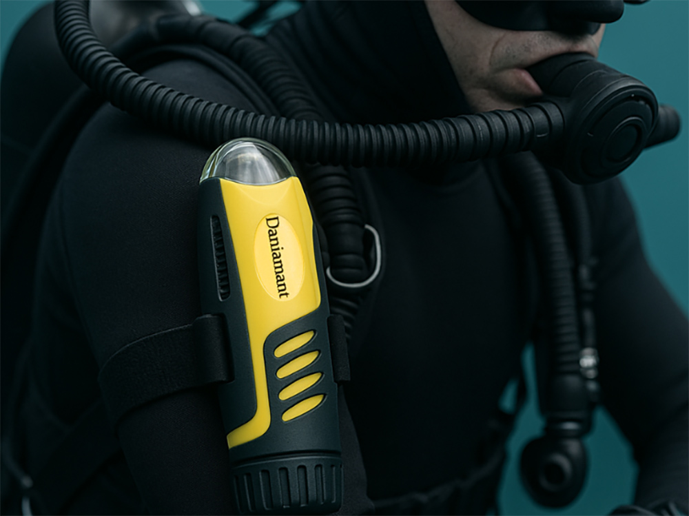 Diver wearing a black wetsuit with a Daniamant AQ-4 MKII yellow strobe light mounted on the shoulder during an underwater operation.