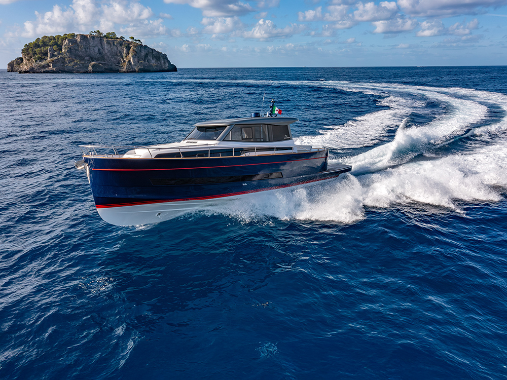 Apreamare Gozzo 48 Cabin cruising off a rocky Mediterranean island.