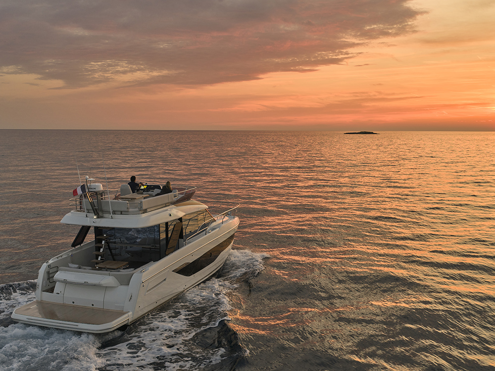 Prestige F4.3 flybridge yacht cruising at sunset on calm sea.