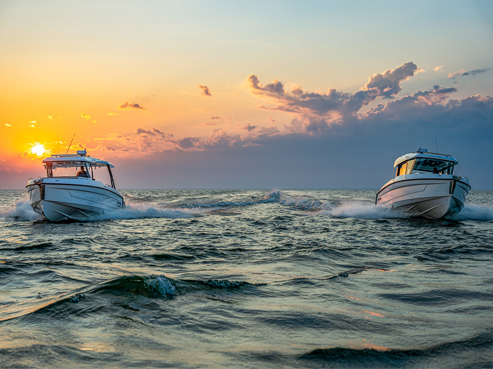 Two Cruisers Yachts 38 VTR boats running side by side at sunset on open water.